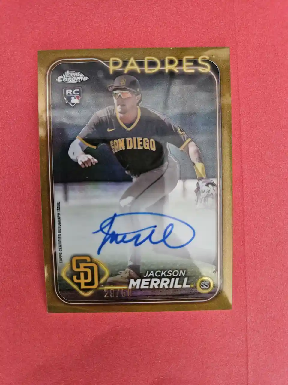 A gold-framed Topps Chrome baseball card of Jackson Merrill, a San Diego Padres rookie (RC), shows him in a black and gold…