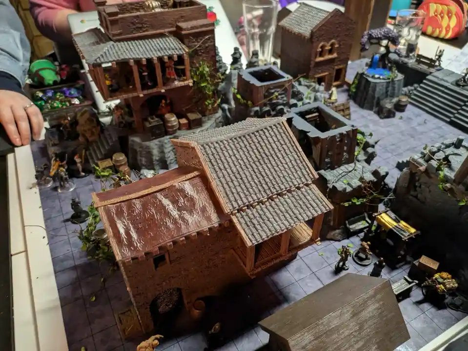 A detailed miniature diorama of a fantasy town made entirely from chocolate, featuring chocolate buildings with tiled roofs…
