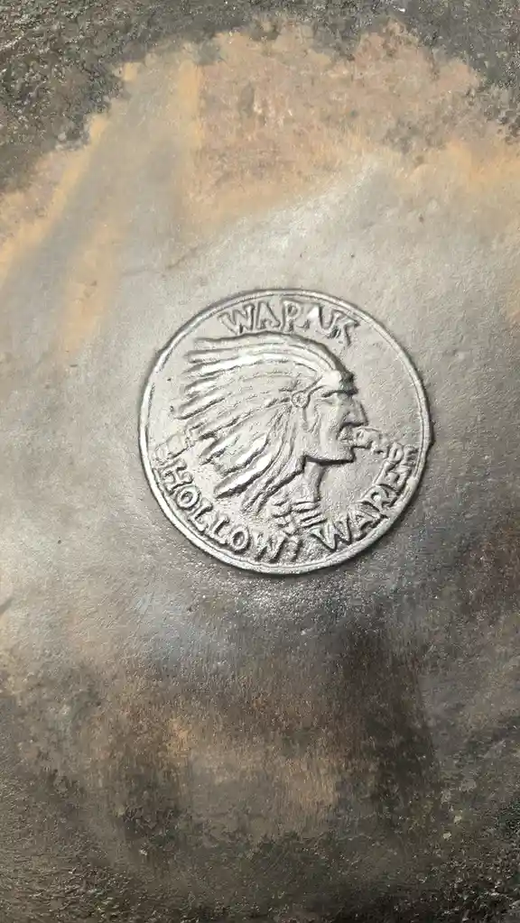 A close-up of a circular metal embossment on a rusted, textured surface, depicting a Native American profile in a feathered…