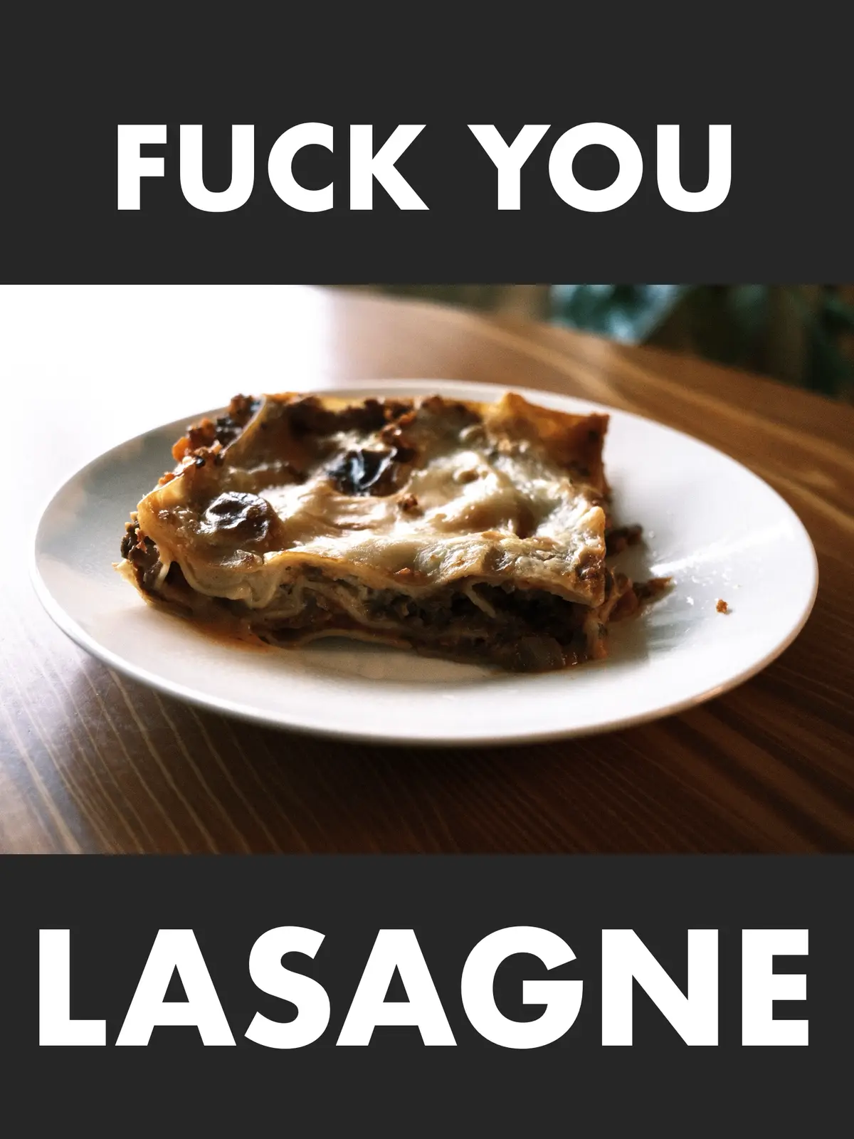 A slice of lasagne with melted cheese and meat sauce sits on a white plate atop a wooden table. The image has bold white…