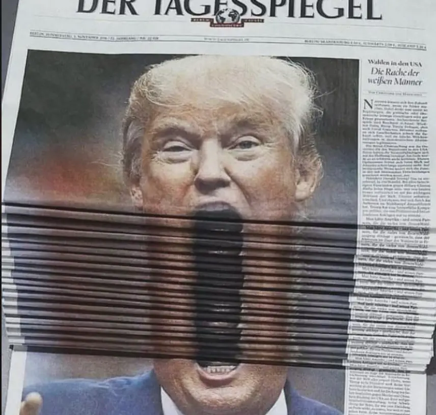 A German newspaper, 'Der Tagesspiegel', features a large photo of Donald Trump with his mouth obscured by a stack of…