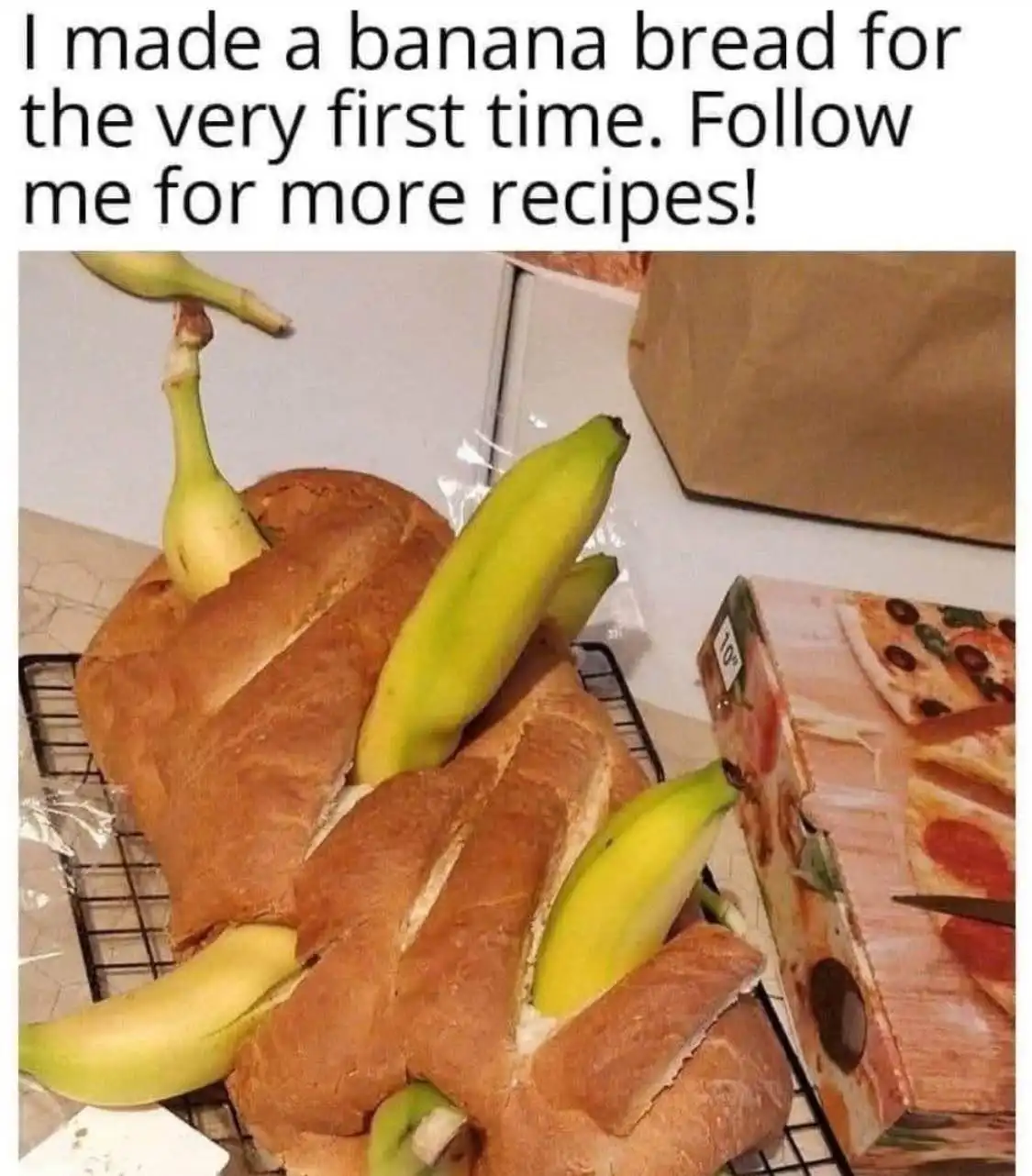 A large, golden-brown loaf of bread sits on a cooling rack, with several green and yellow bananas visibly stuck into its…