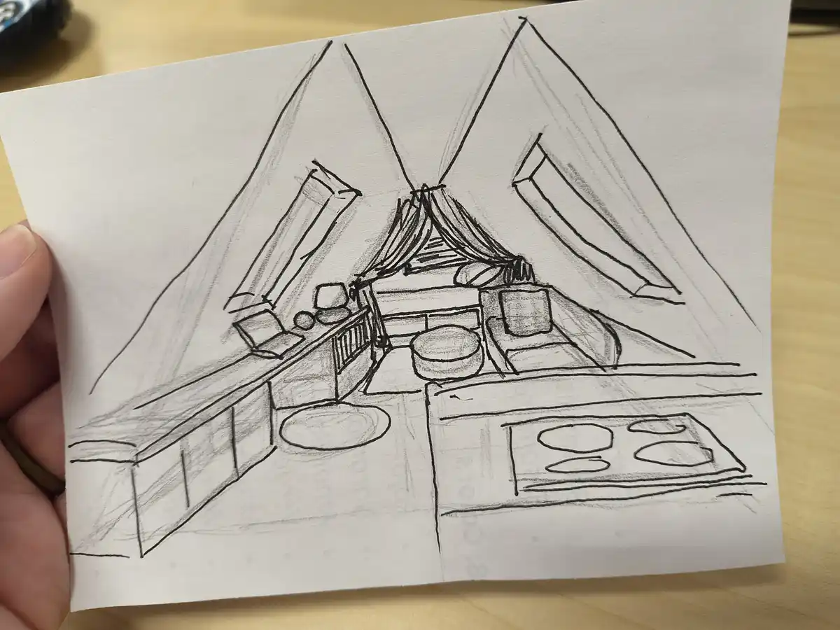 A hand holds a pencil sketch of a minimalist apartment interior, showing a bed with curtains, a kitchenette with stove…