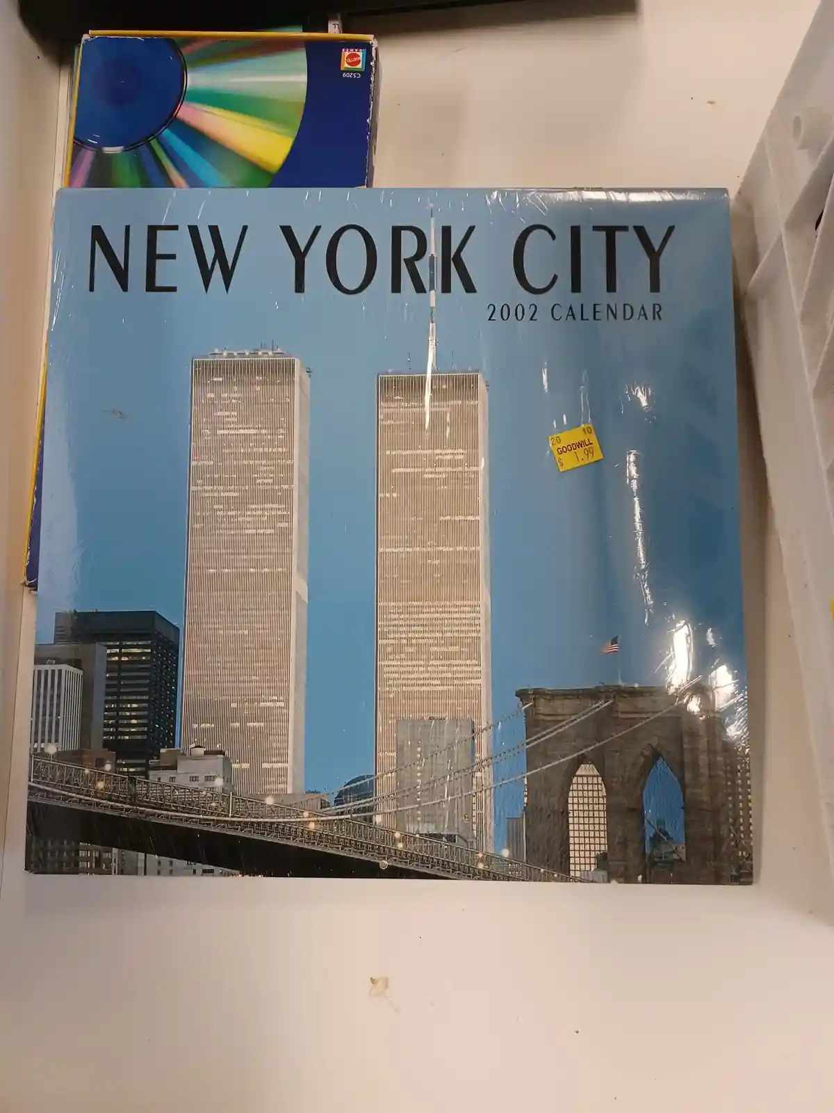 A 2002 New York City calendar cover showing the Twin Towers and Brooklyn Bridge, still sealed in plastic with a Goodwill…