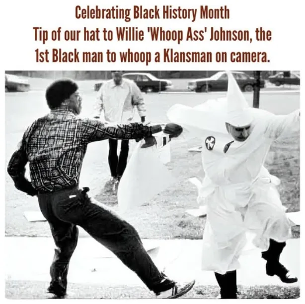 A black-and-white photo shows a Black man in a plaid shirt punching a white man in a Ku Klux Klan robe and hood. The…