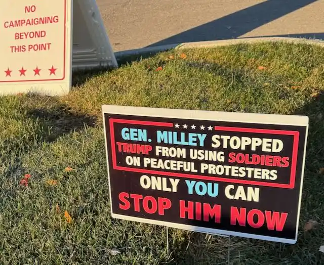 A protest sign on grass reads 'GEN. MILLEY STOPPED TRUMP FROM USING SOLDIERS ON PEACEFUL PROTESTERS ONLY YOU CAN STOP HIM…