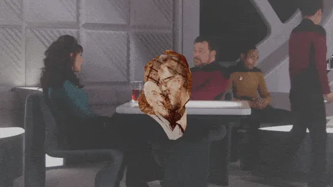 A sequence of frames from a Star Trek scene shows a man in a red uniform sitting at a table, with his face progressively…