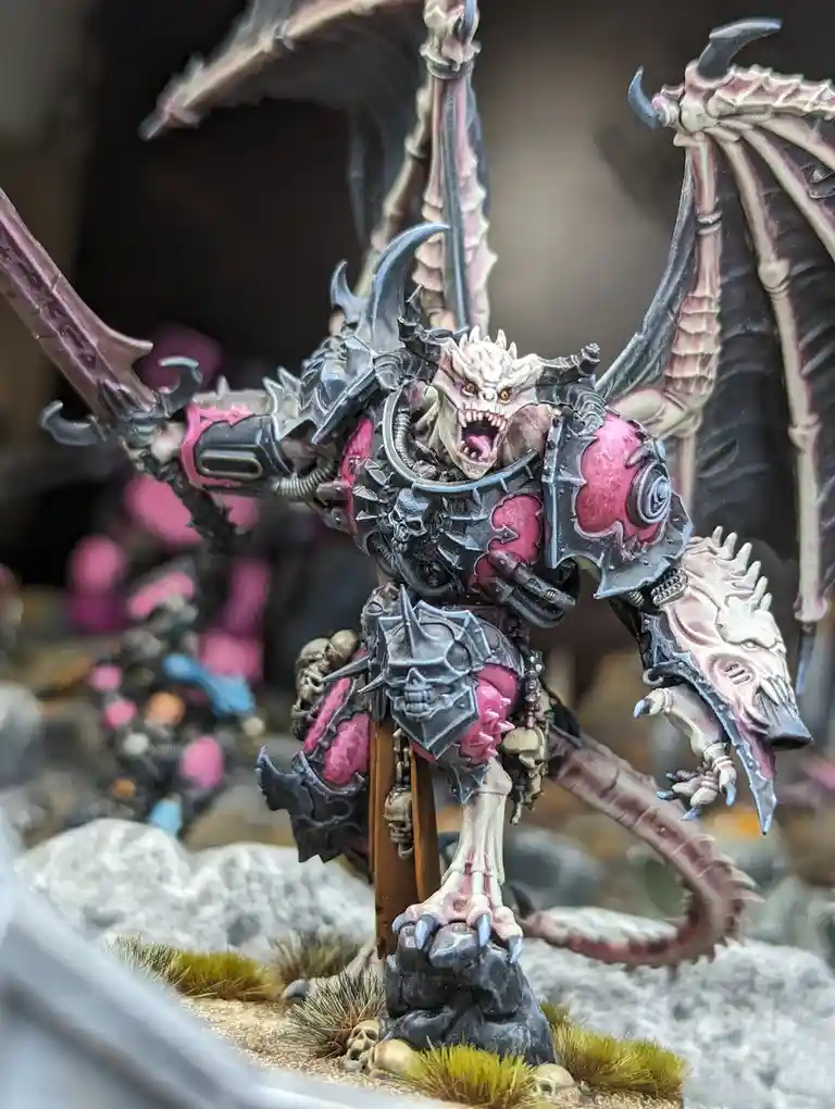 A highly detailed, painted miniature of a demonic, winged creature with a skeletal dragon-like body, pink and black armor…