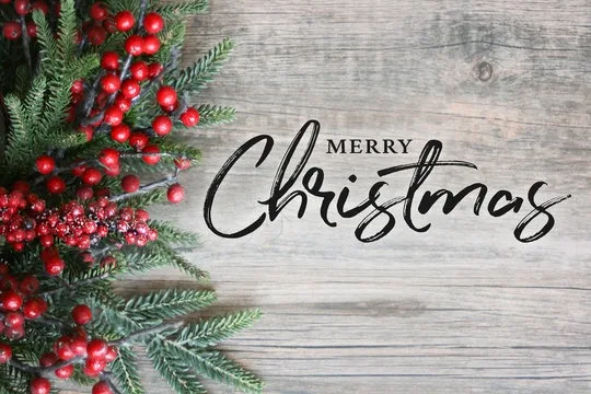 A festive image shows a rustic wooden surface with a decorative arrangement of green pine branches and clusters of bright…