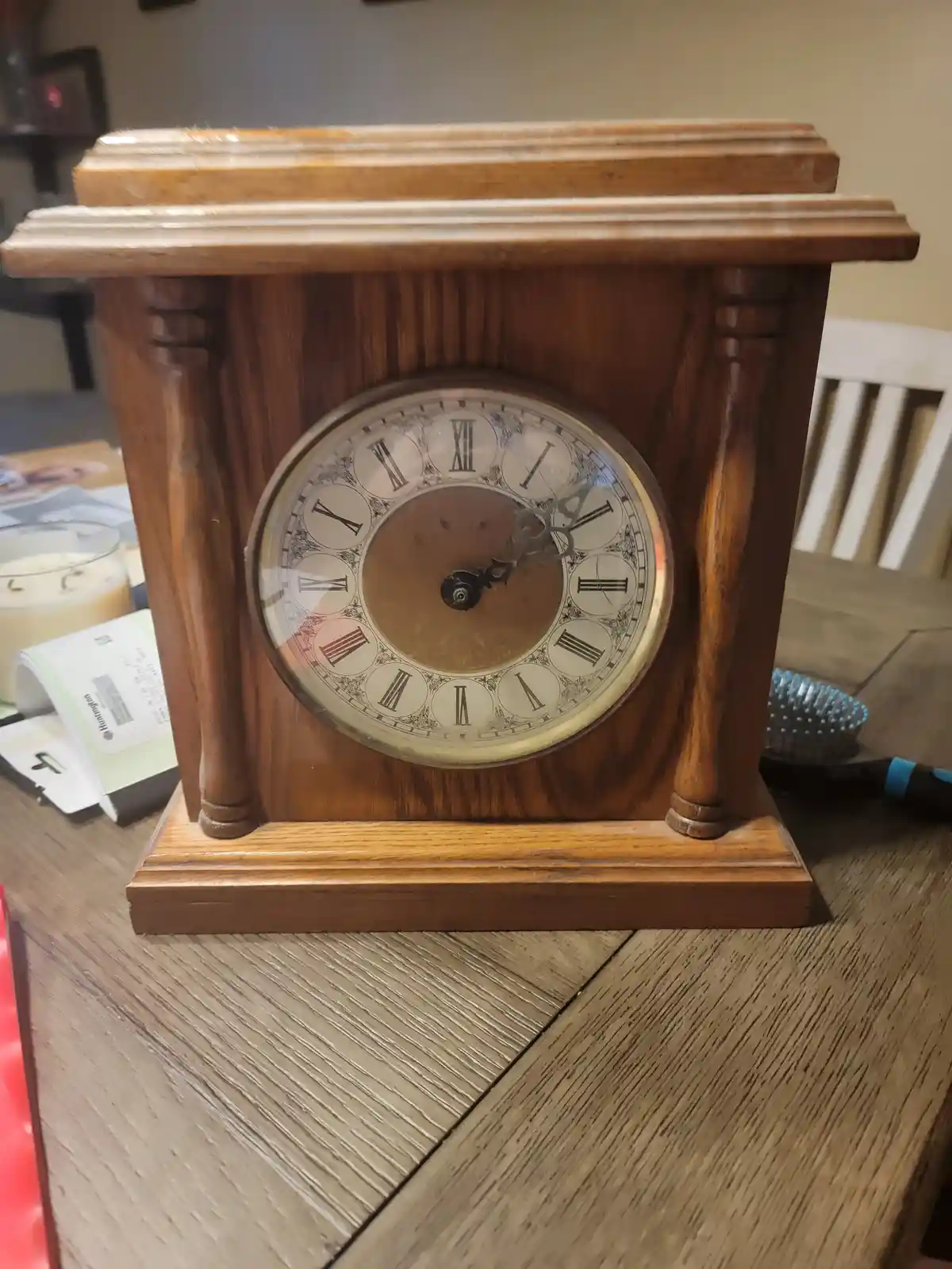A close-up photo of a wooden mantel clock with Roman numerals, showing the time as approximately 10:10. The clock's hands…