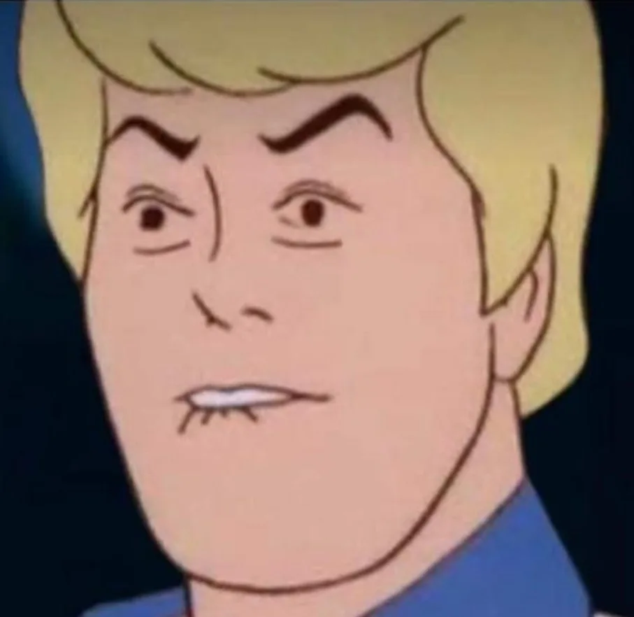 a close-up of a cartoon man with blonde hair and a blue collar, his eyebrows are furrowed and his mouth is set in a grimace…