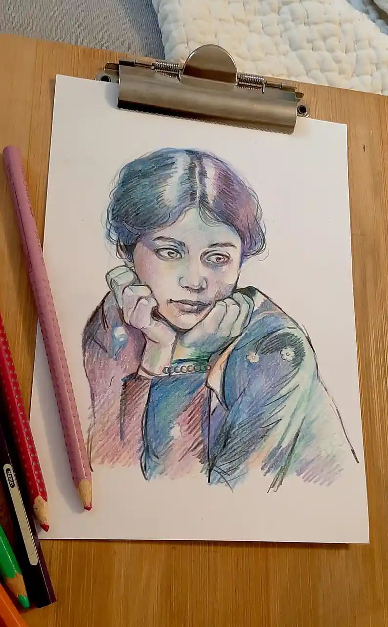 A colored pencil drawing of a young person with short hair, resting their chin on their hands, is clipped to a clipboard on…