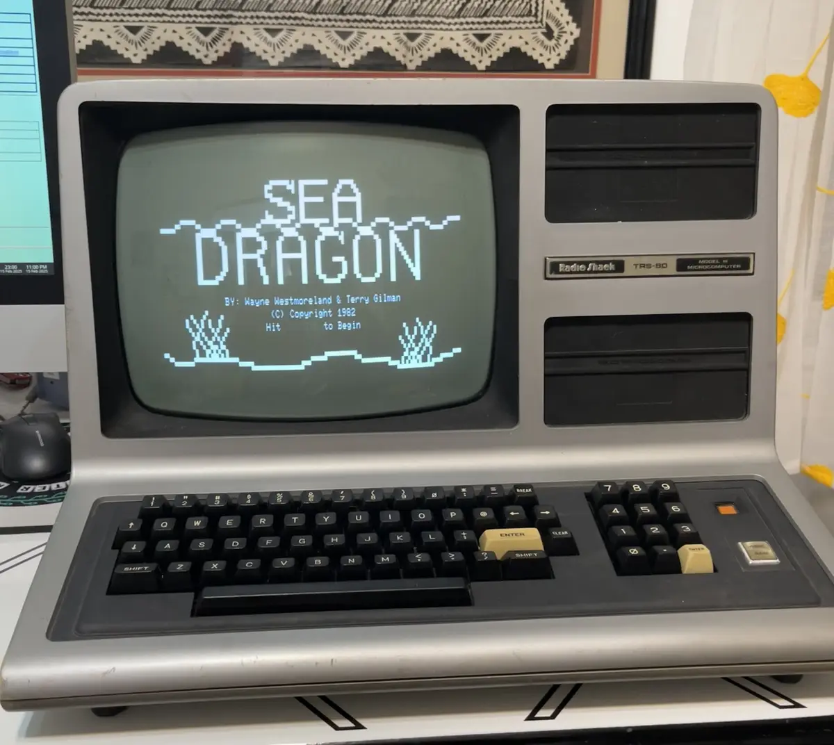 A vintage Radio Shack TRS-80 Model III microcomputer displays the title screen of the 1982 game 'Sea Dragon,' featuring…