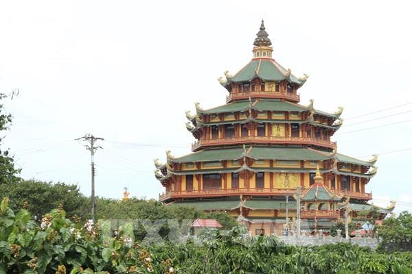 a multi-tiered, ornate east asian temple with green roofs and wooden structures stands behind green foliage under an…