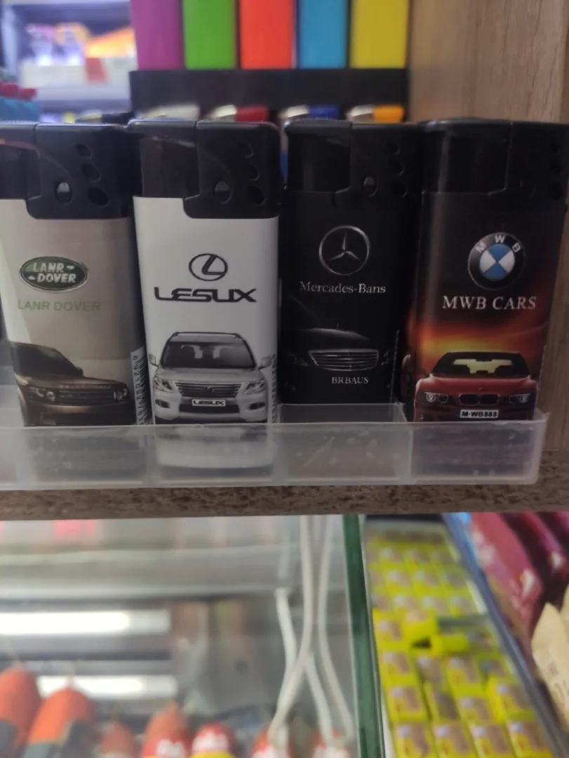 Four branded lighters sit side-by-side in a clear plastic tray, each featuring a car brand logo and image: 'Lanr Dover'…