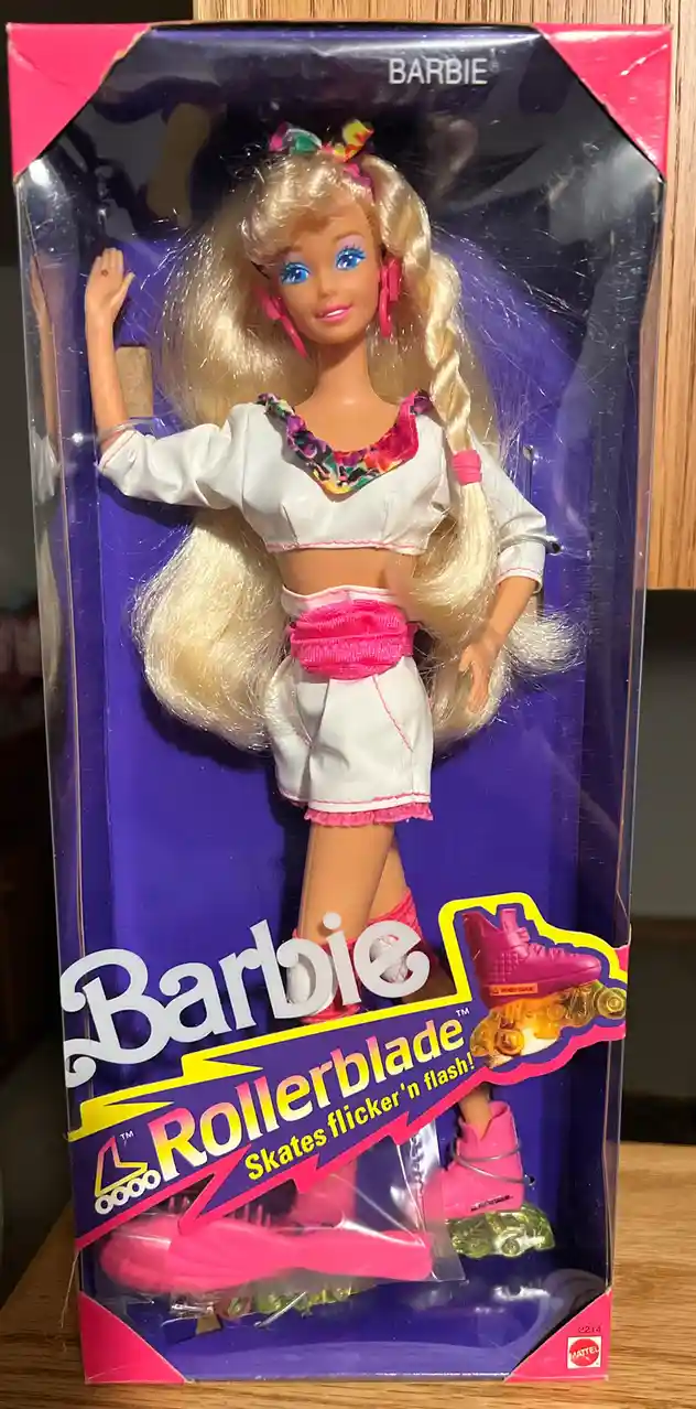 A vintage Barbie doll in her original packaging, wearing a white crop top and shorts with pink accessories and rollerblades…