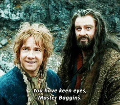 Two men from The Lord of the Rings stand side by side; the man on the left smiles while the man on the right looks at him…