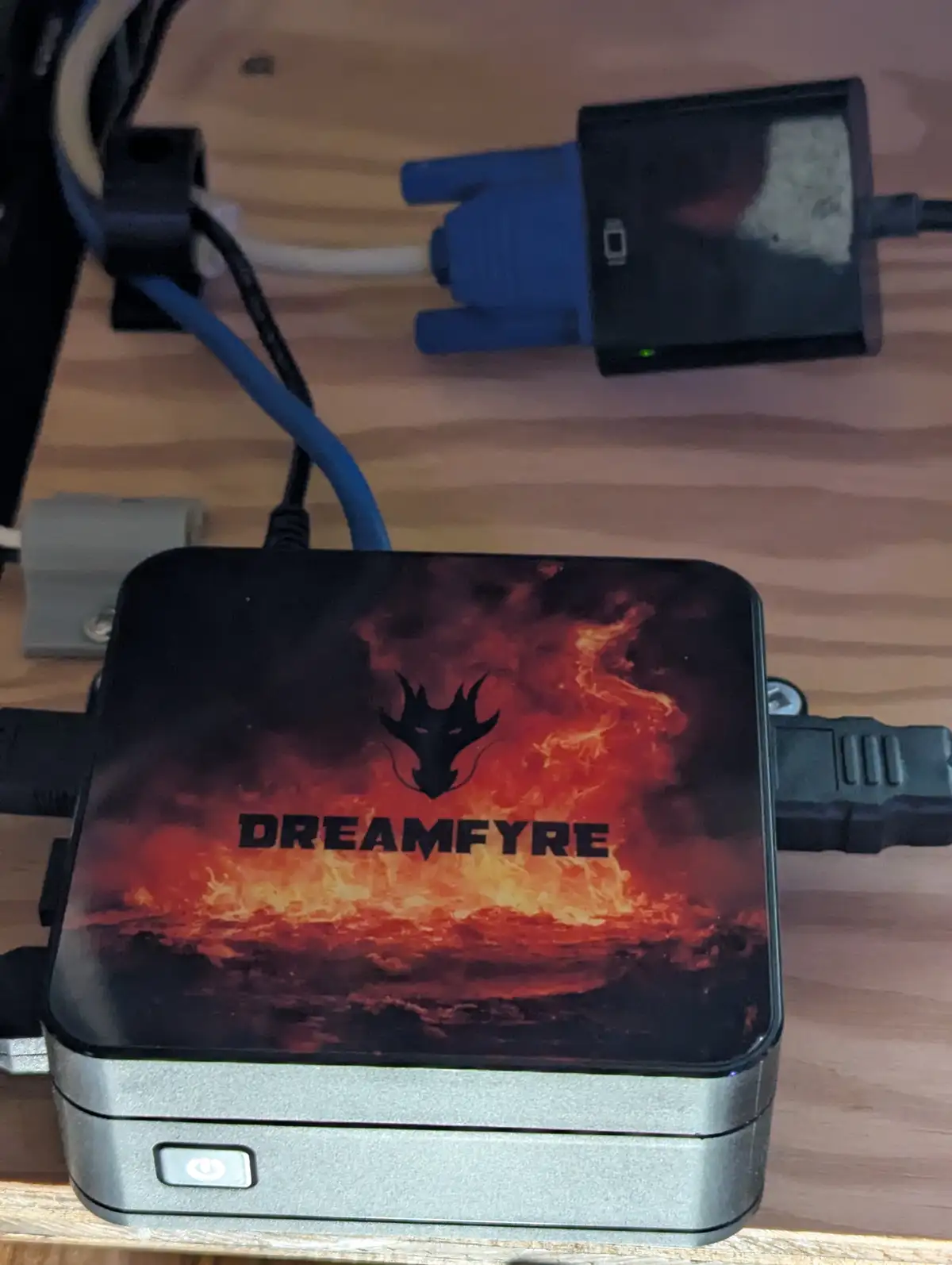 A small black and silver electronic device with a fiery dragon logo and the word 'DREAMFYRE' printed on its top surface sits…