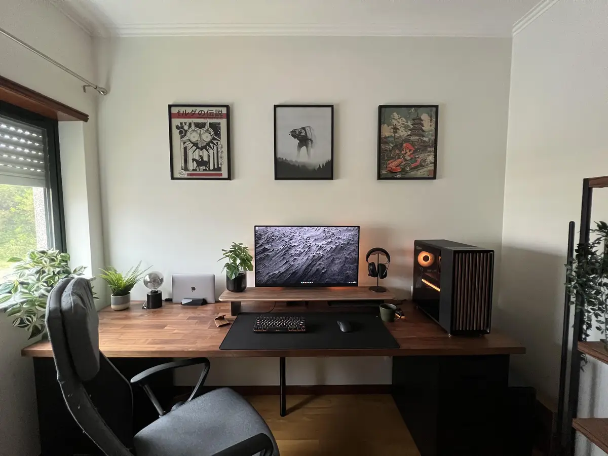 A clean, modern home office desk with a wooden surface, black chair, and computer setup including a monitor, keyboard…