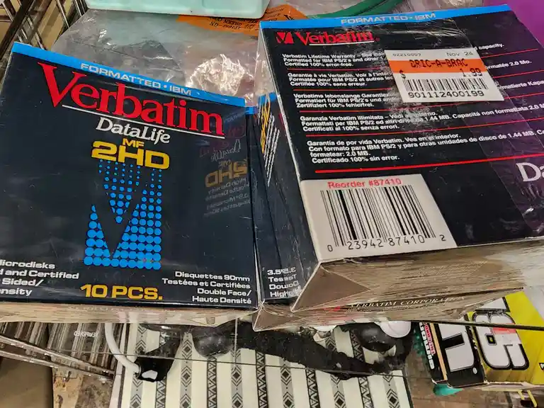 Two boxes of vintage Verbatim 3.5-inch high-density floppy disks, labeled 'Formatted • IBM' and '10 PCS.', sit on a shelf…