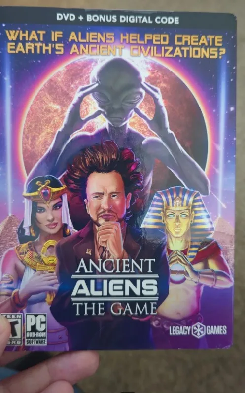 A person holds a video game box titled 'Ancient Aliens: The Game' by Legacy Games. The cover art features a large alien…