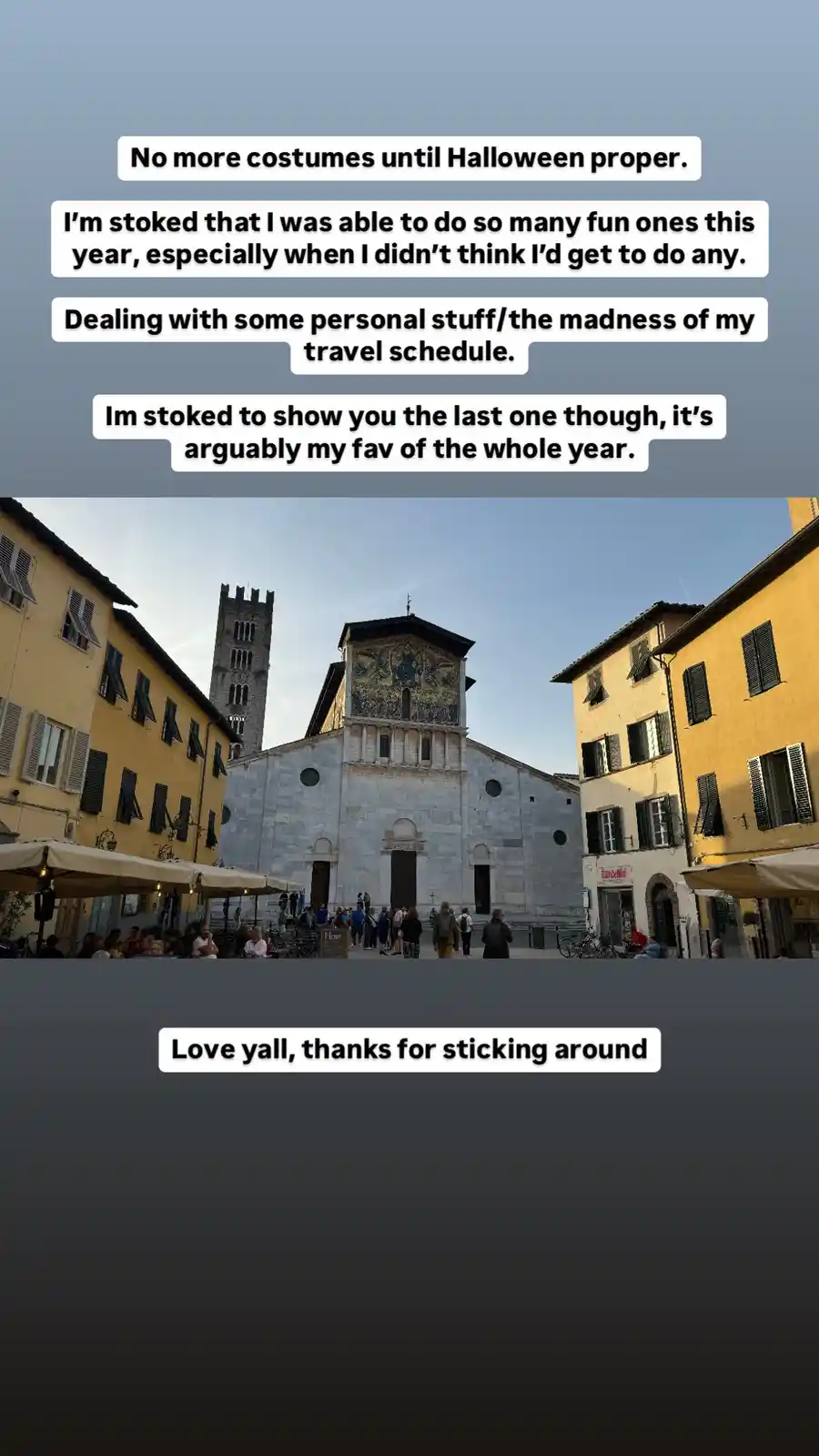 The image shows a European-style town square with yellow buildings, outdoor cafe seating, and a large stone church with a…