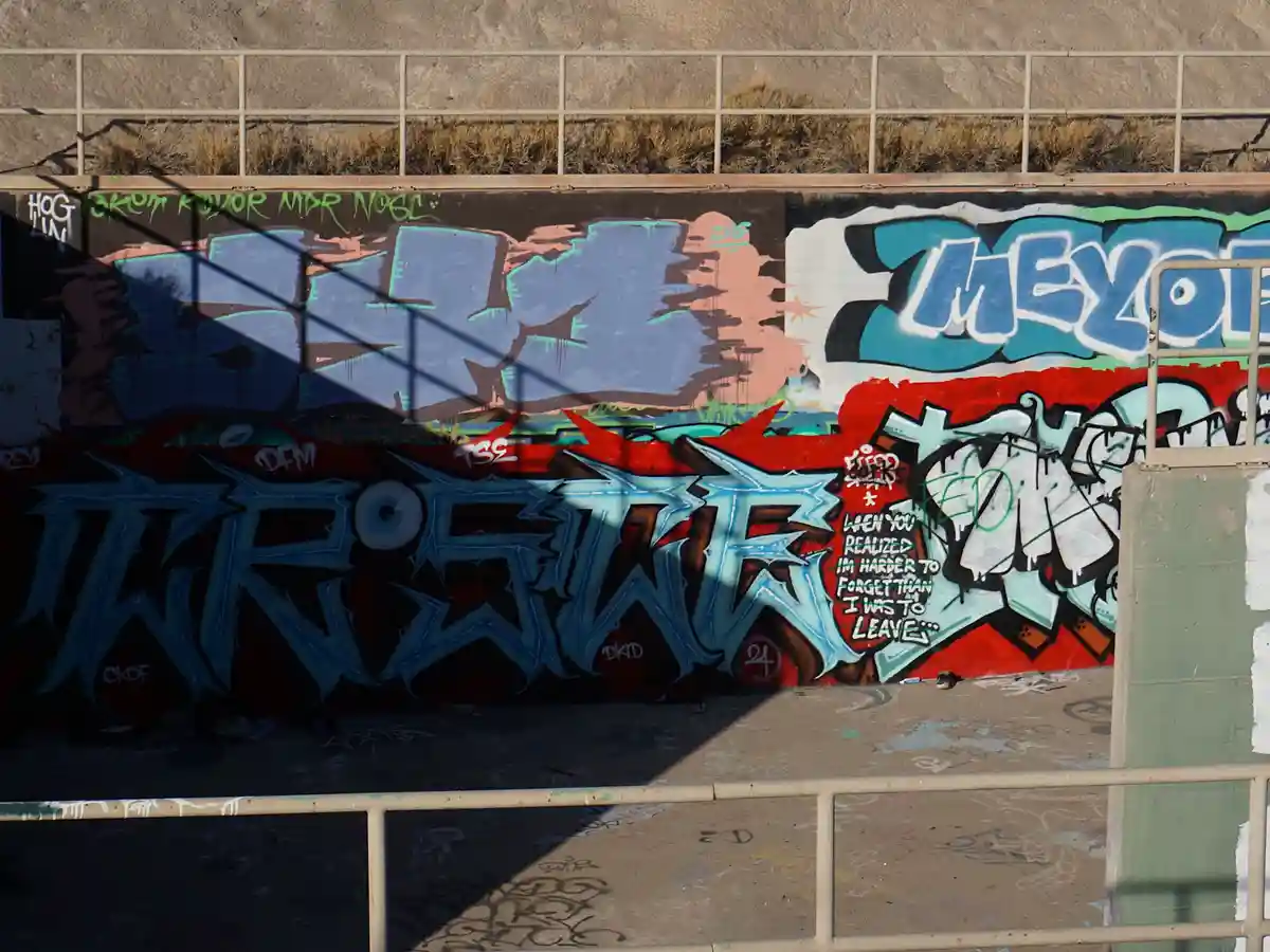 A photo of a graffiti-covered wall with various colorful tags and stylized lettering. Overlaid on a small red section is the…