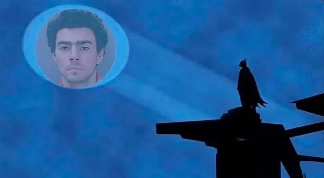 A silhouette of a person standing atop a structure against a blue sky, with a circular projection of a man's face hovering…