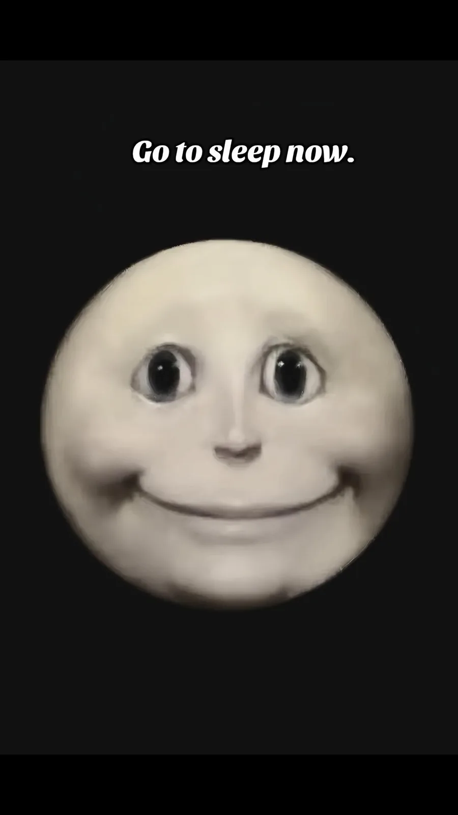 A black and white image features a round, smiling face with large, wide eyes against a dark background. The overlaid text…