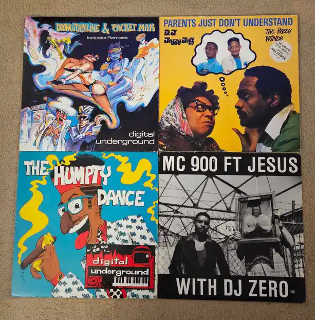 Four vintage hip-hop vinyl record covers are laid out on a carpet. Top left: 'Doowutchyalike & Packet Man' by Digital…