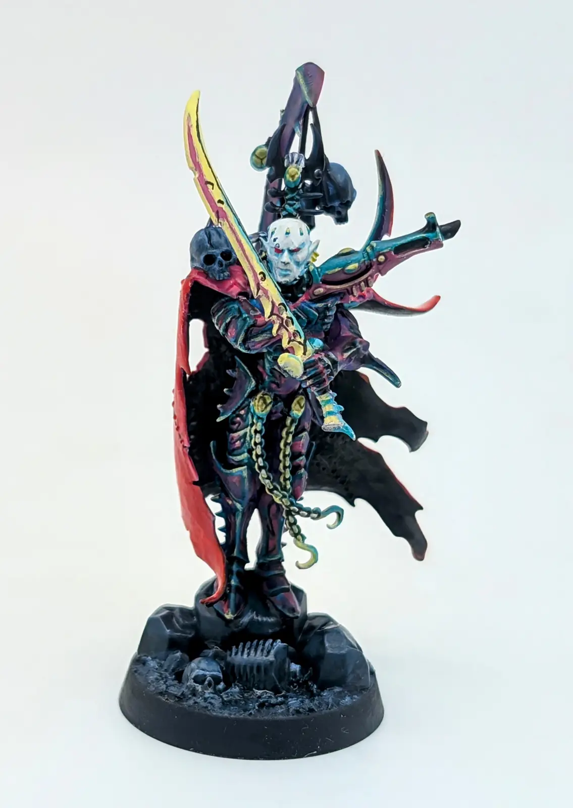 A highly detailed, painted miniature of a fantasy warrior with pale blue skin, red eyes, and a red cape, wielding a large…
