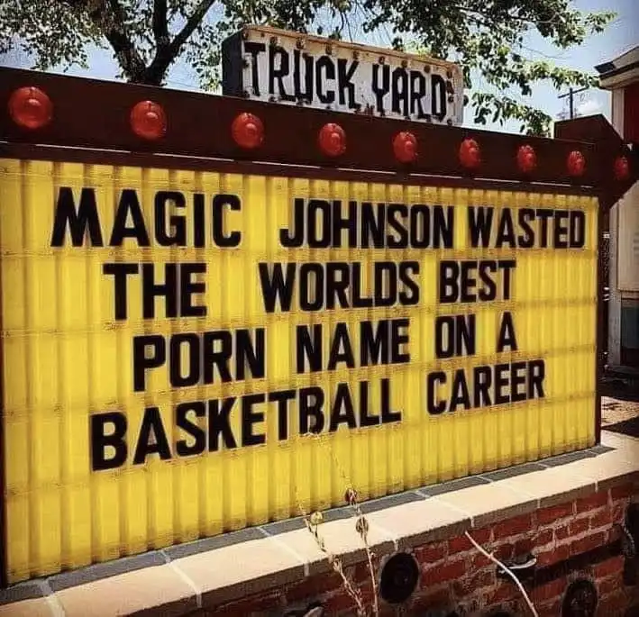 A yellow theater marquee with black lettering reads 'MAGIC JOHNSON WASTED THE WORLDS BEST PORN NAME ON A BASKETBALL CAREER'…