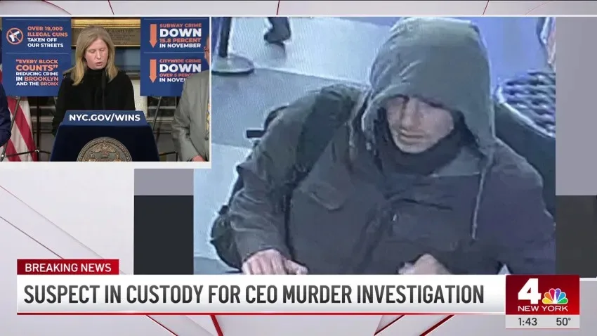 A split-screen news broadcast shows a woman at a podium with NYC.gov/WINS banners behind her, alongside a grainy security…
