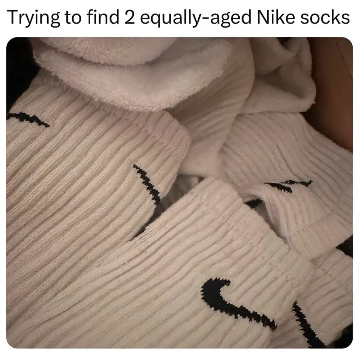 A close-up photo shows a pile of off-white, ribbed knit socks with black Nike swoosh logos, visibly mismatched in wear and…