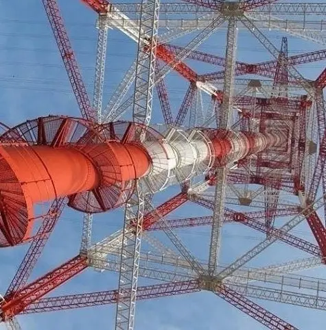 A low-angle photo looking up at a tall, red and white lattice tower against a blue sky, with overlaid text reading 'i'm not…