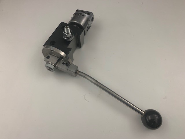 a close-up photo of a metallic hydraulic directional control valve with a long lever handle ending in a black knob, set…