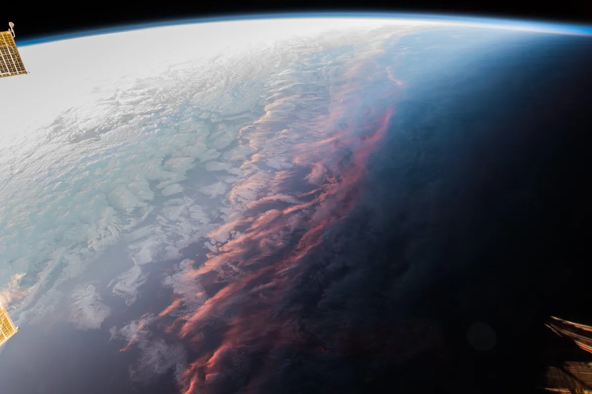 A stunning space photograph shows the curved horizon of Earth from orbit, with a dramatic transition from bright…