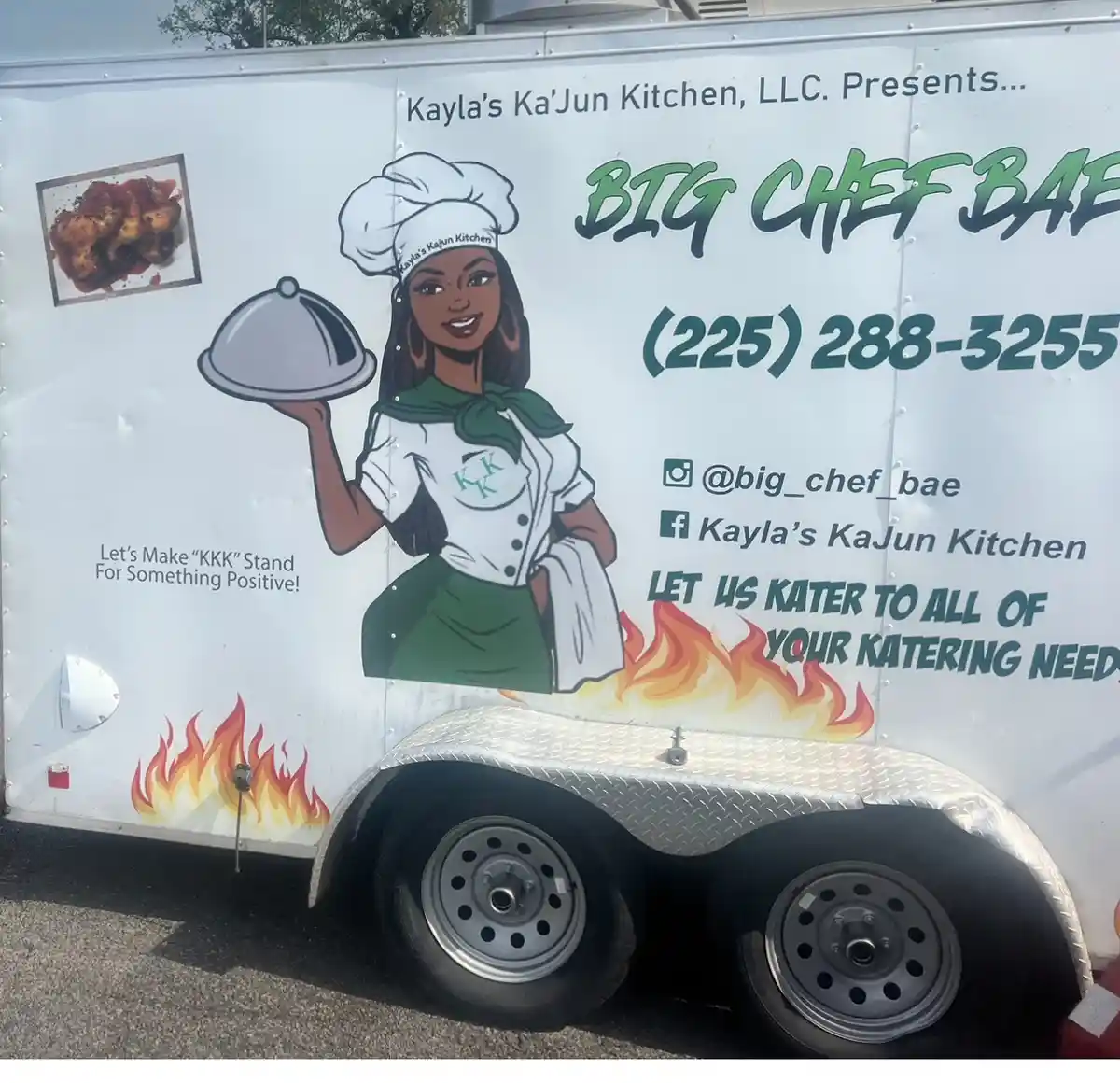 A white food truck features a cartoon illustration of a smiling Black female chef in a white chef's hat and green apron…