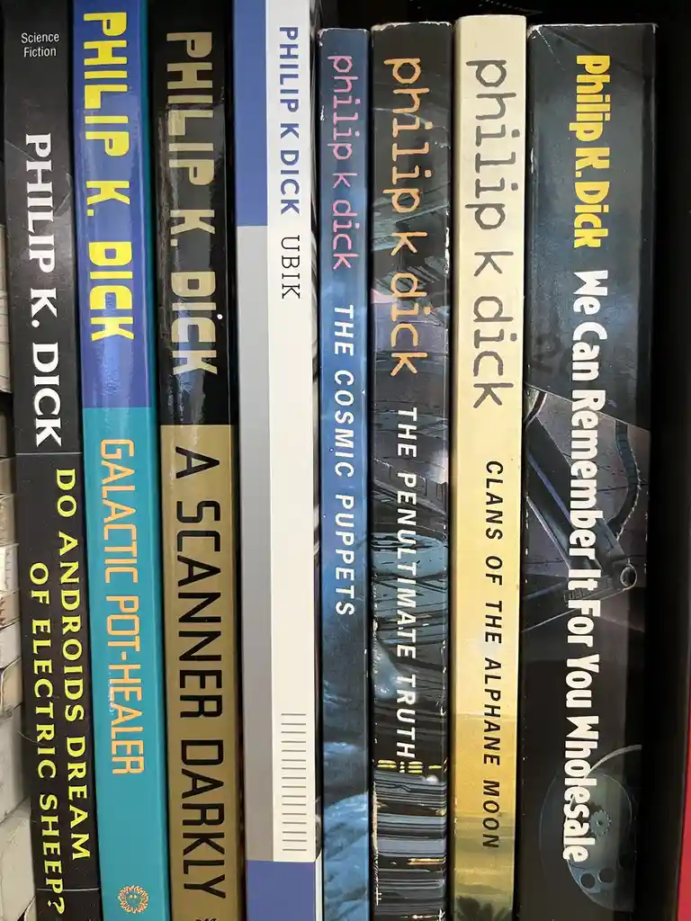 A close-up shot of a bookshelf displaying multiple books by Philip K. Dick, including titles like 'Do Androids Dream of…