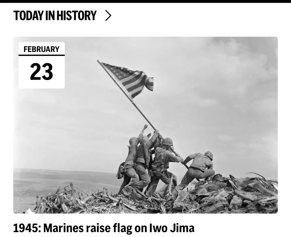 A black-and-white historical photo shows five U.S. Marines raising the American flag on a volcanic crater at Iwo Jima on…