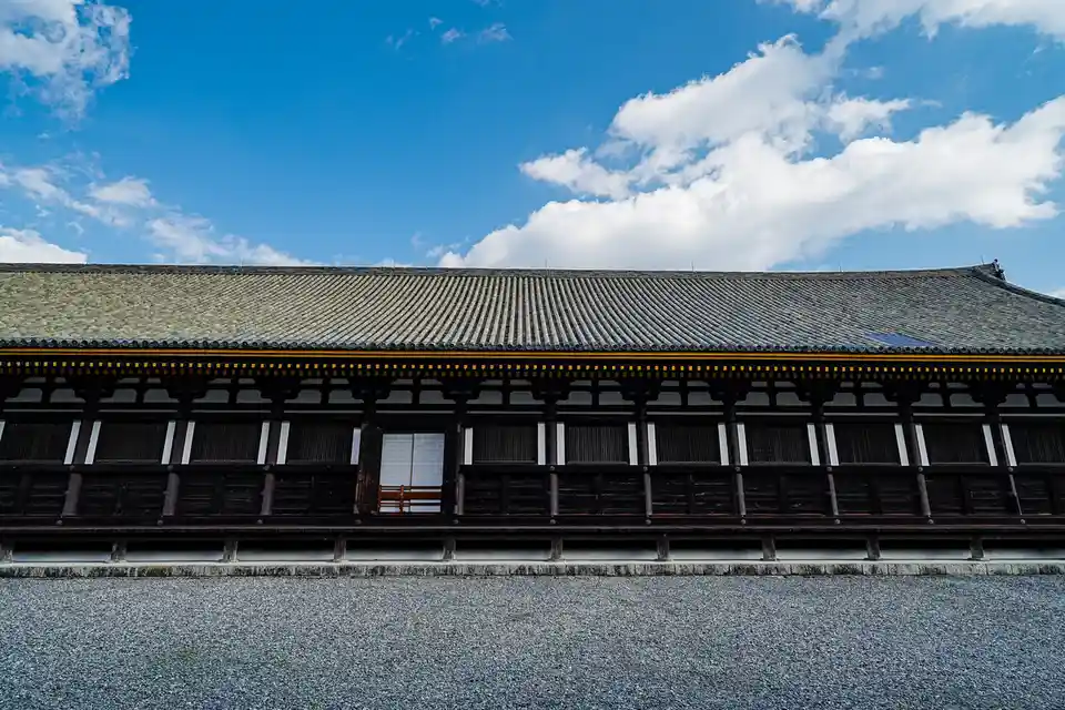 A low-angle shot of a traditional Japanese building with a dark tiled roof and wooden structure under a bright blue sky with…