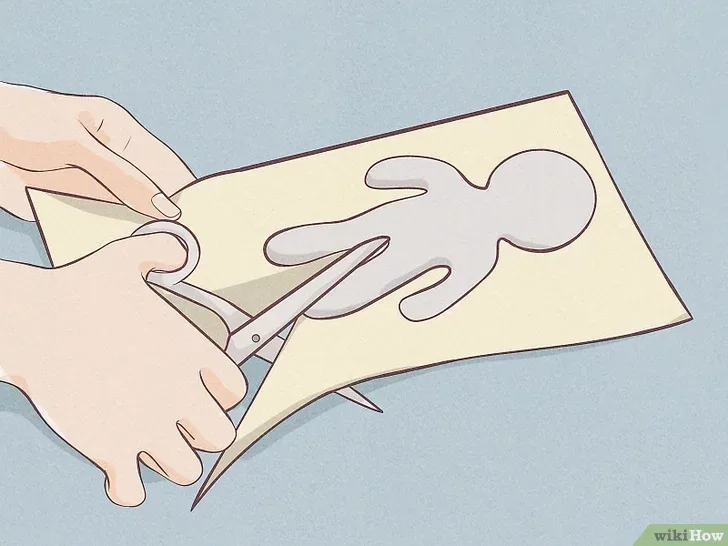 An illustrated image shows two hands cutting out a simple human-shaped silhouette from a piece of light-colored paper using…