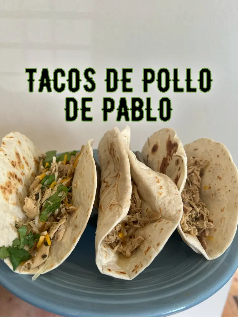 Three chicken tacos on a blue plate, filled with shredded chicken, cheese, and cilantro, with bold green text overlaid that…